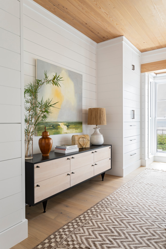 Example of a huge beach style master light wood floor, beige floor, wood ceiling and shiplap wall bedroom design in Charleston with white walls