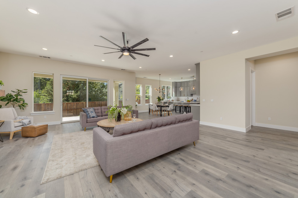 This is an example of a mid-sized transitional open concept living room in Sacramento with beige walls, laminate floors and grey floor.