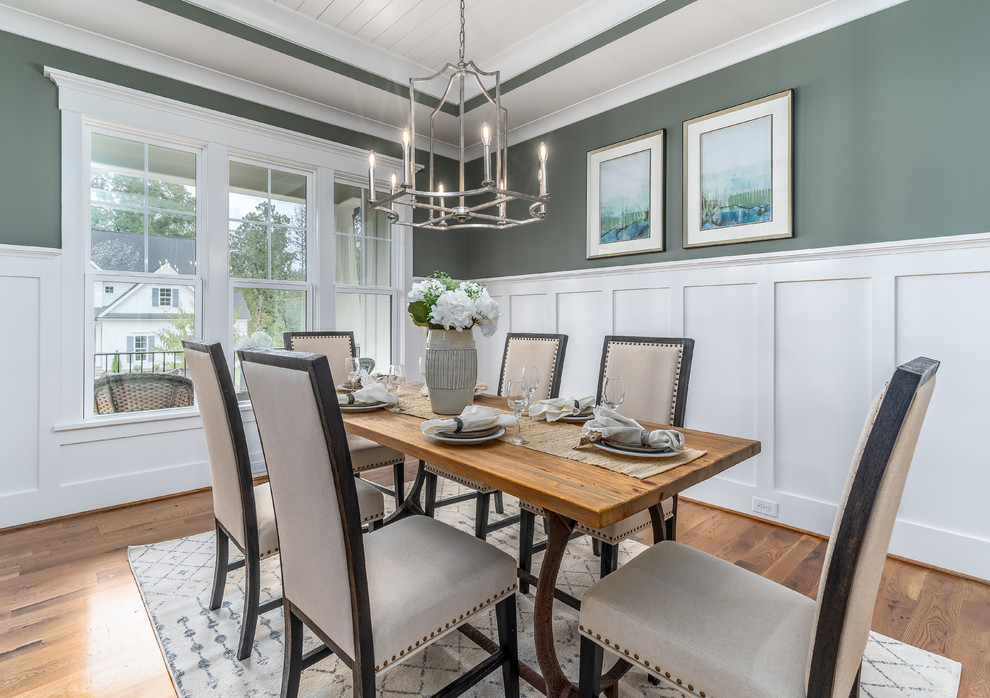 Photo of a country separate dining room in Raleigh with green walls, medium hardwood floors and brown floor.