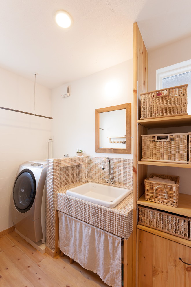 Photo of an asian laundry room in Other with open cabinets, white walls, medium hardwood floors and brown floor.