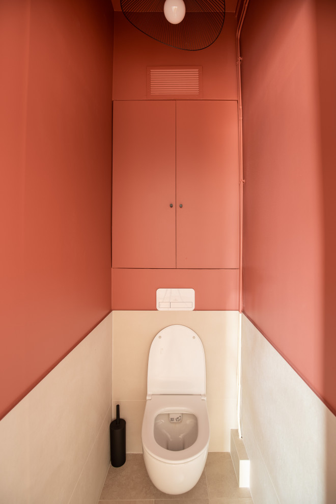 Mittelgroße Klassische Gästetoilette mit Kassettenfronten, orangefarbenen Schränken, Wandtoilette, oranger Wandfarbe, Keramikboden, beigem Boden und eingebautem Waschtisch in Paris