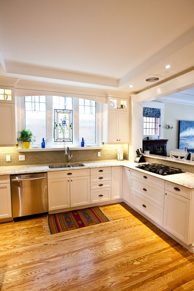 Mid-sized transitional u-shaped medium tone wood floor and brown floor eat-in kitchen photo in Toronto with an undermount sink, white cabinets, quartzite countertops, stainless steel appliances, a peninsula, recessed-panel cabinets, gray backsplash and glass tile backsplash