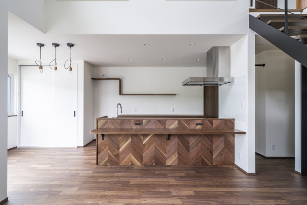 Inspiration för mellanstora moderna linjära brunt kök med öppen planlösning, med en undermonterad diskho, luckor med profilerade fronter, bruna skåp, träbänkskiva, vitt stänkskydd, stänkskydd i porslinskakel, mörkt trägolv, en köksö och brunt golv
