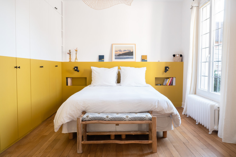 Aménagement d'une chambre parentale moderne de taille moyenne avec un mur jaune, parquet clair, aucune cheminée et dressing.