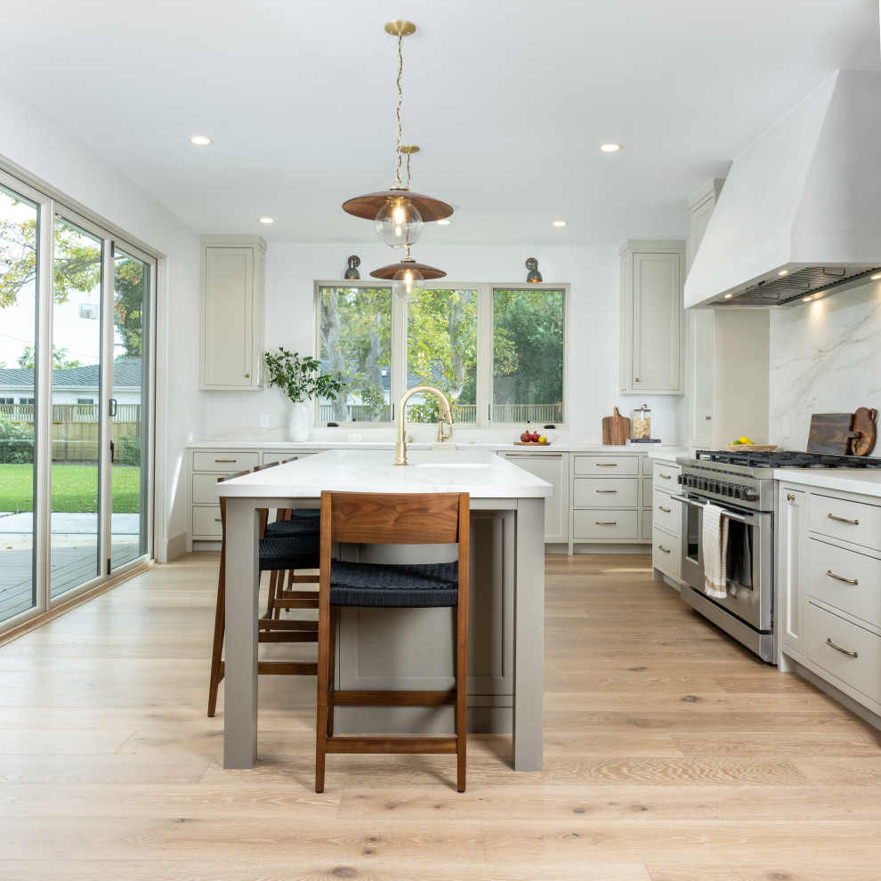 This is an example of a large traditional galley open plan kitchen in San Francisco with an undermount sink, beaded inset cabinets, beige cabinets, quartz benchtops, white splashback, engineered quartz splashback, panelled appliances, light hardwood floors, with island, brown floor, white benchtop and exposed beam.