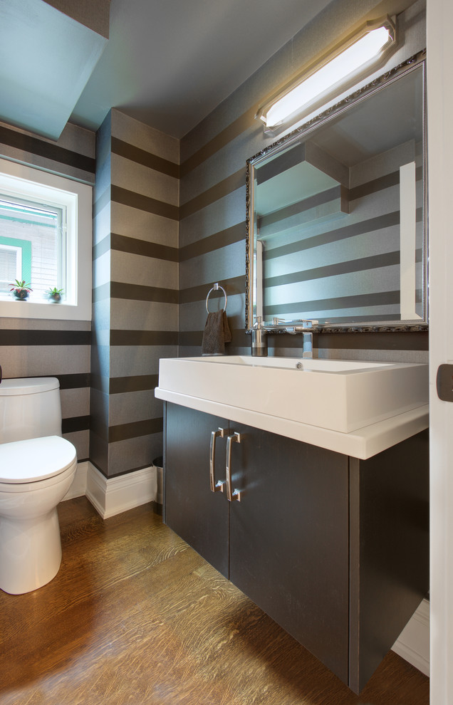 This is an example of a small transitional 3/4 bathroom in Toronto with a vessel sink, flat-panel cabinets, grey cabinets, engineered quartz benchtops, a two-piece toilet, black walls and medium hardwood floors.