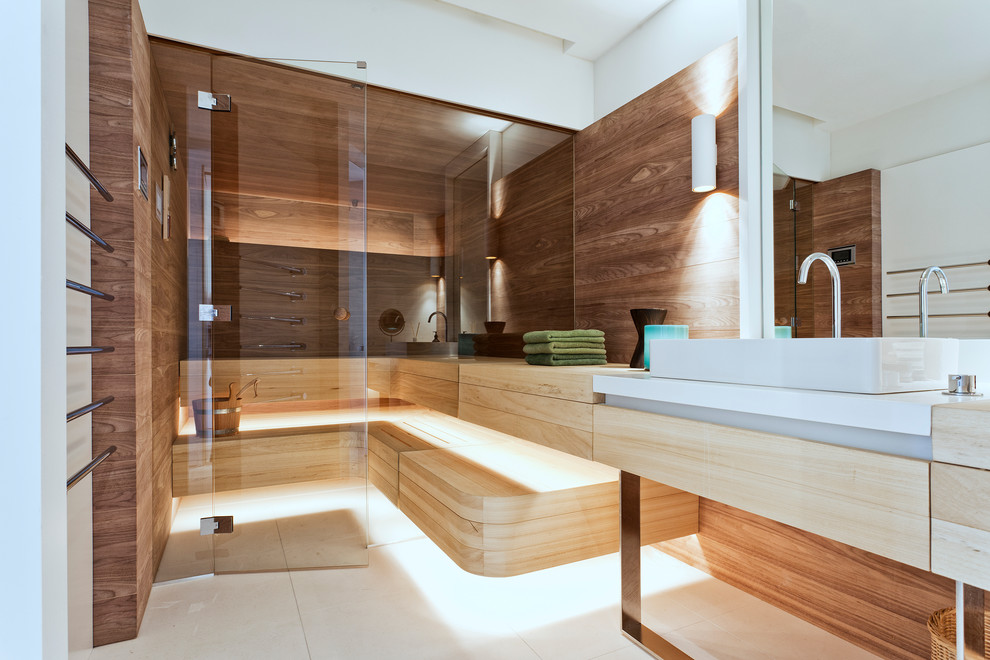 This is an example of a mid-sized contemporary bathroom in Berlin with flat-panel cabinets, white cabinets, a freestanding tub, beige tile, stone slab, white walls, limestone floors, a vessel sink, limestone benchtops and with a sauna.