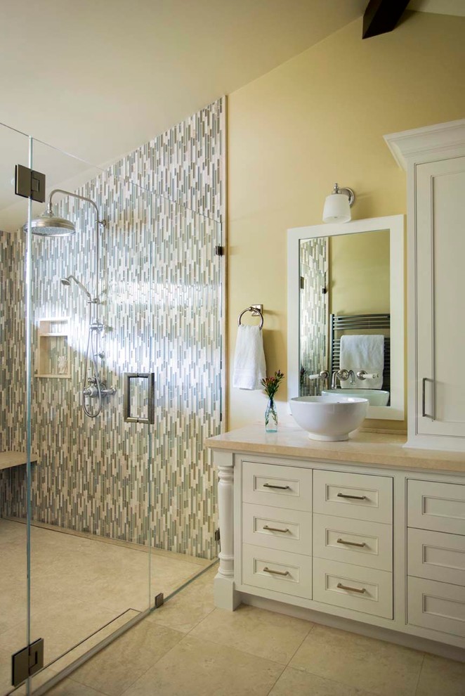 This is an example of a large country master bathroom in San Francisco with furniture-like cabinets, white cabinets, a double shower, a one-piece toilet, multi-coloured tile, glass sheet wall, yellow walls, limestone floors, an undermount sink and limestone benchtops.