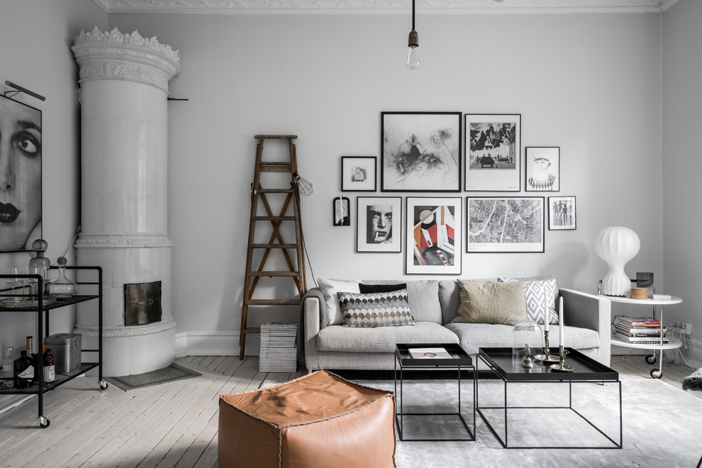 Inspiration for a mid-sized scandinavian enclosed living room in Gothenburg with light hardwood floors, a tile fireplace surround, grey walls, a wood stove and grey floor.