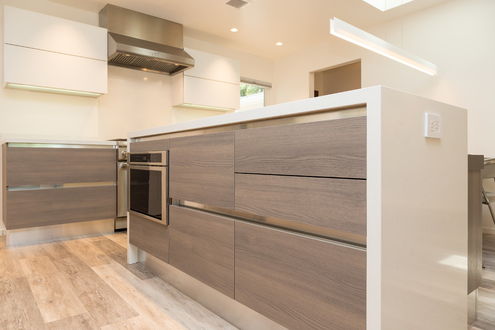 Photo of a mid-sized modern l-shaped eat-in kitchen in San Francisco with an undermount sink, flat-panel cabinets, light wood cabinets, quartz benchtops, white splashback, glass tile splashback, stainless steel appliances, laminate floors, with island and beige floor.