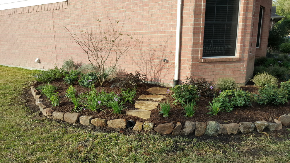 This is an example of a mid-sized traditional side yard xeriscape in Houston with a container garden and natural stone pavers.