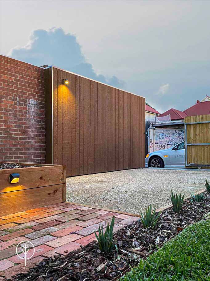 Mittelgroßer Moderner Garten im Frühling, hinter dem Haus mit Auffahrt, Hochbeet, direkter Sonneneinstrahlung, Granitsplitt und Holzzaun in Melbourne