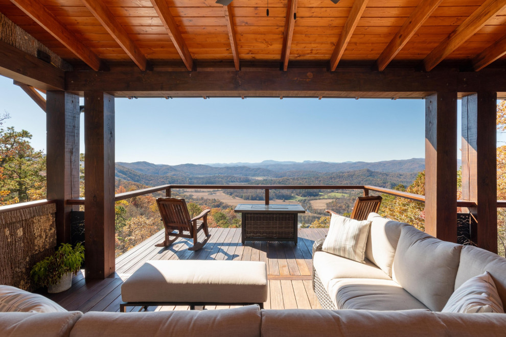 Example of a mountain style backyard second story metal railing deck design with a roof extension