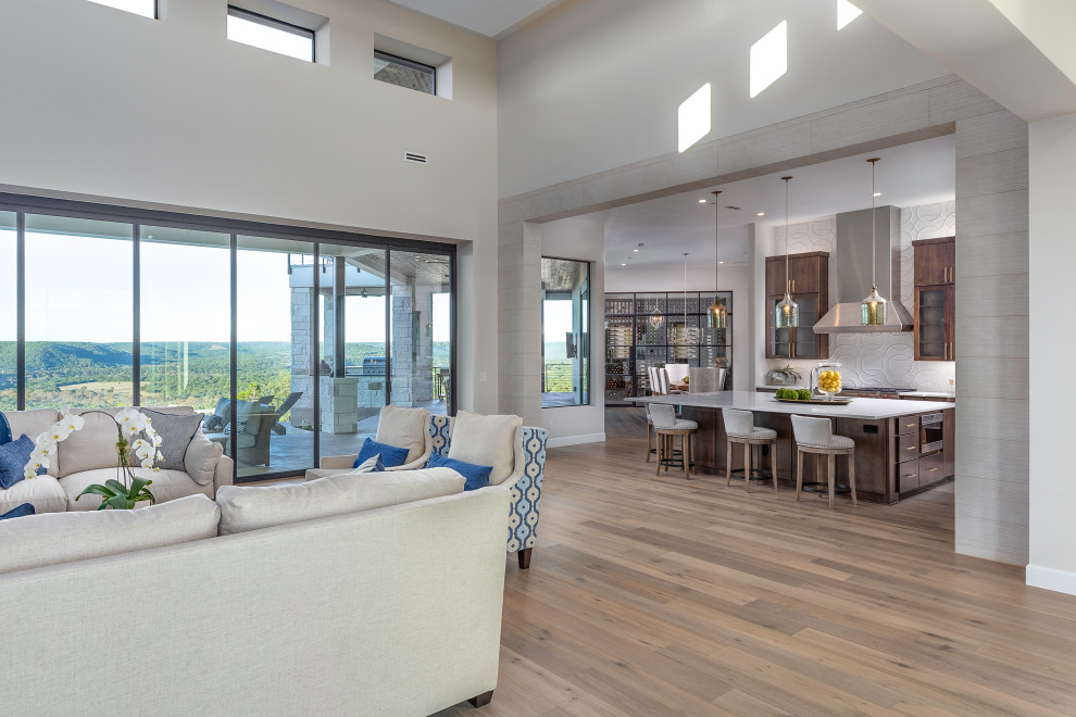 Inspiration for a transitional open concept family room in Austin with white walls, light hardwood floors and beige floor.