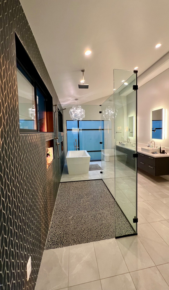 Design ideas for an expansive modern master bathroom in Hawaii with flat-panel cabinets, dark wood cabinets, a freestanding tub, a curbless shower, blue tile, mosaic tile, porcelain floors, a vessel sink, engineered quartz benchtops, grey floor, an open shower, white benchtops, a double vanity, a floating vanity, vaulted and a bidet.