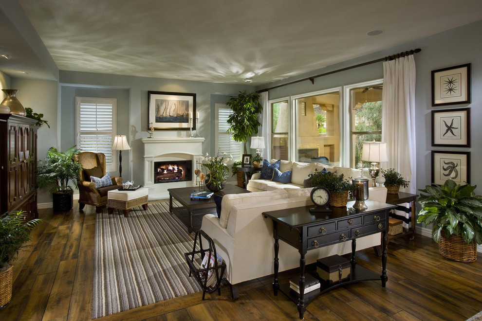 This is an example of a large traditional formal open concept living room in Las Vegas with blue walls, dark hardwood floors, a standard fireplace, a plaster fireplace surround and multi-coloured floor.