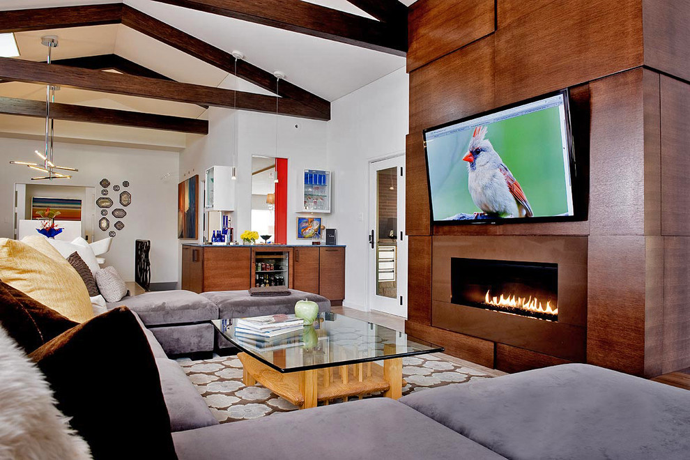 Design ideas for a large contemporary open concept family room in Other with a home bar, dark hardwood floors, a standard fireplace, a wood fireplace surround and a wall-mounted tv.