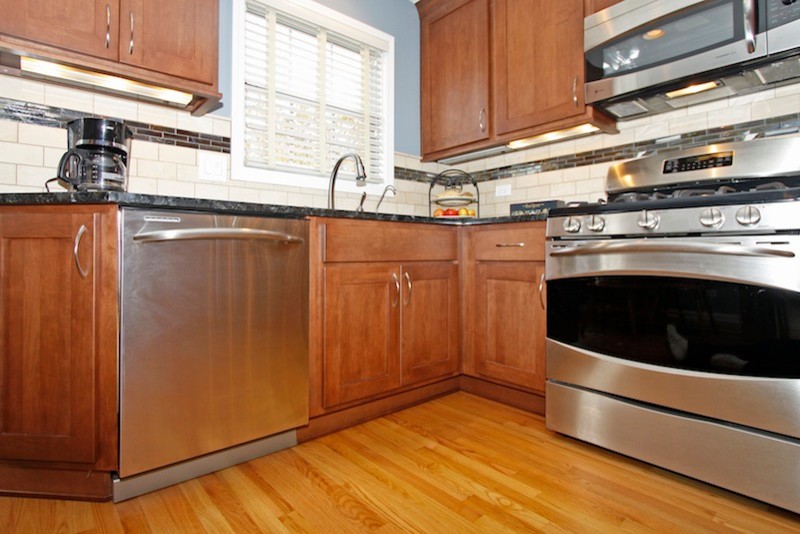 Eat-in kitchen - mid-sized transitional u-shaped light wood floor eat-in kitchen idea in Chicago with an undermount sink, recessed-panel cabinets, medium tone wood cabinets, granite countertops, beige backsplash, stone tile backsplash, stainless steel appliances and no island