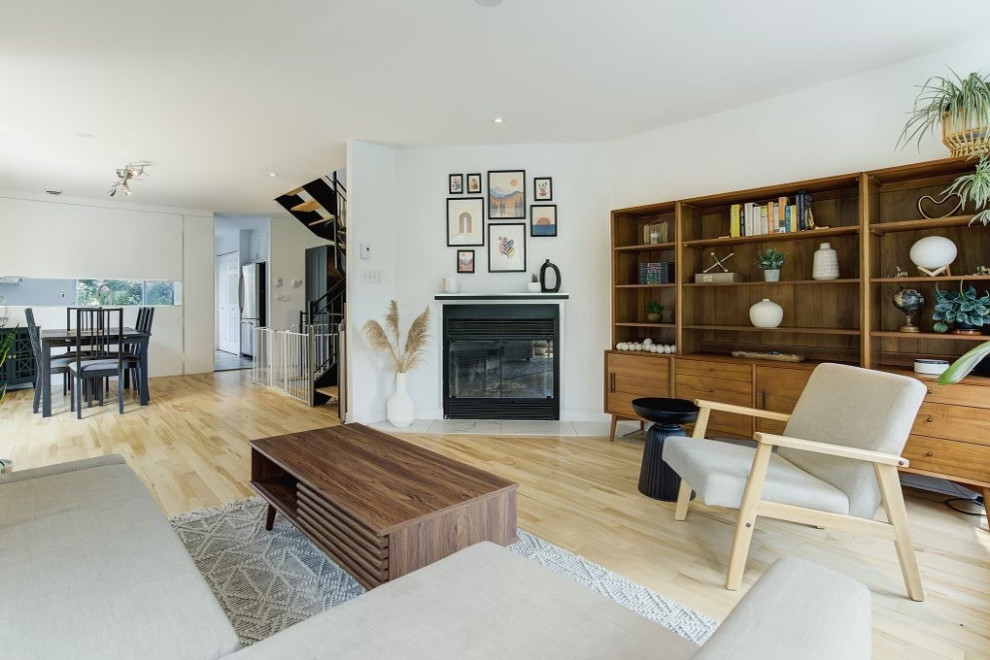 Design ideas for a mid-sized midcentury living room in Montreal with white walls, light hardwood floors, a standard fireplace, a metal fireplace surround and yellow floor.
