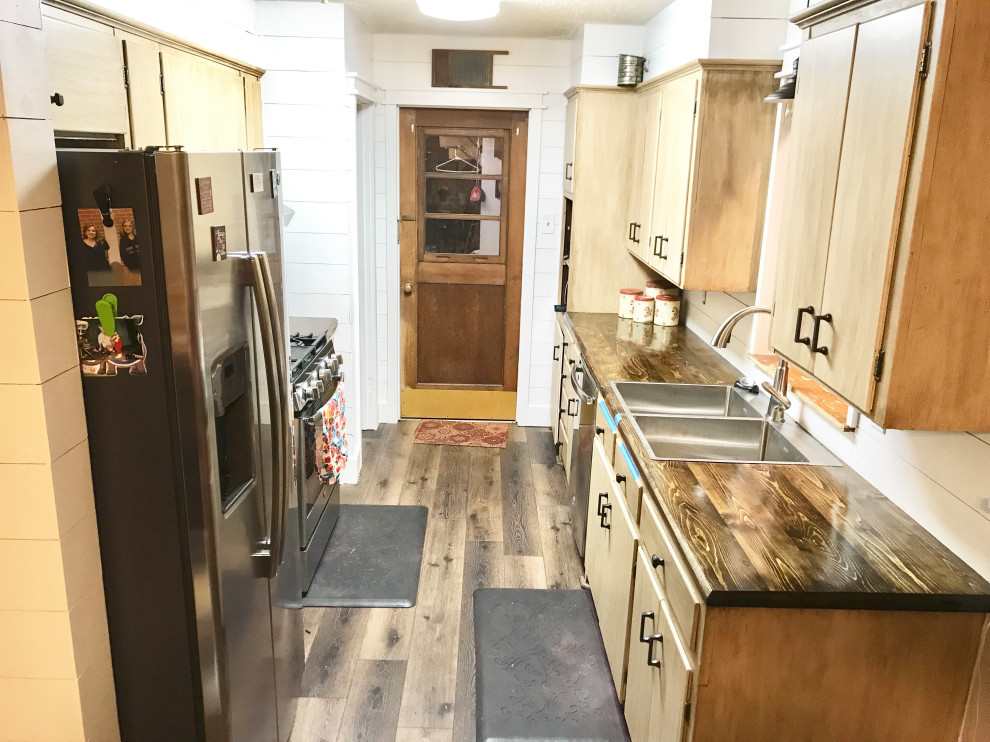 Small country galley kitchen pantry in Austin with a double-bowl sink, flat-panel cabinets, distressed cabinets, wood benchtops, white splashback, timber splashback, white appliances, laminate floors, no island, brown floor and brown benchtop.