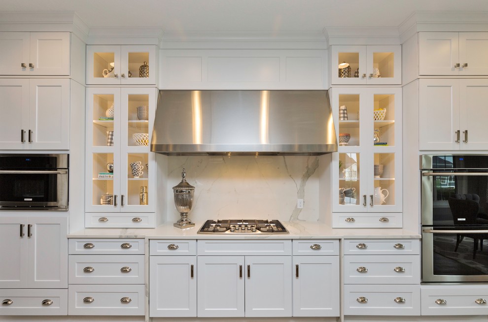 Inspiration for a large transitional l-shaped porcelain tile eat-in kitchen remodel with a farmhouse sink, shaker cabinets, white cabinets, marble countertops, stainless steel appliances and an island