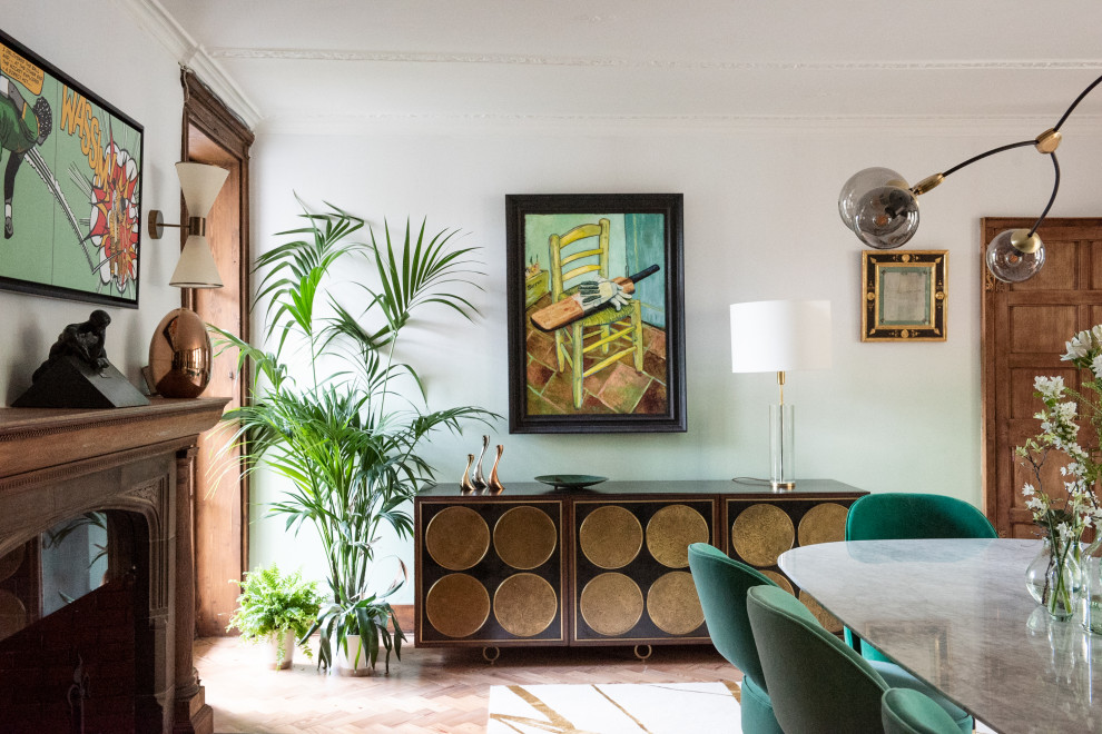 Large eclectic separate dining room in London with green walls, light hardwood floors, a standard fireplace, a stone fireplace surround, beige floor and wallpaper.