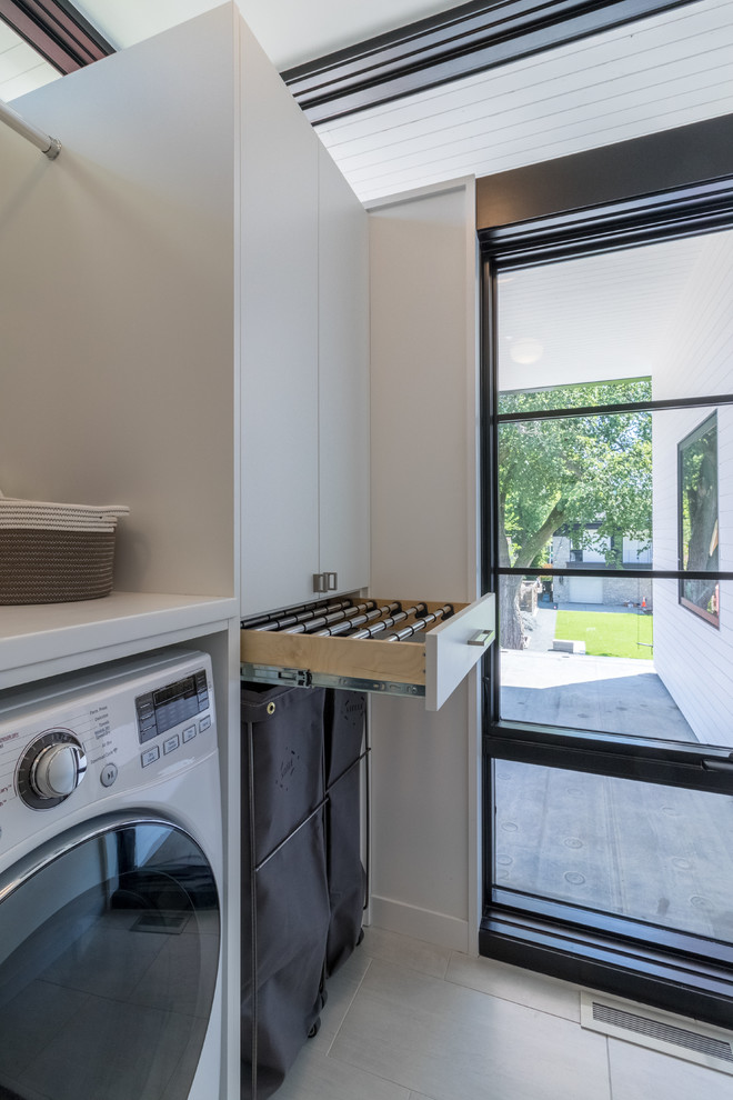 This is an example of a mid-sized modern single-wall dedicated laundry room in Minneapolis with an undermount sink, flat-panel cabinets, white cabinets, quartz benchtops, white walls, porcelain floors, a side-by-side washer and dryer and white floor.