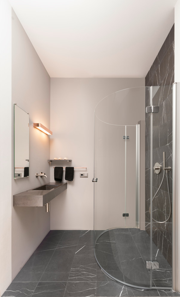 Small contemporary 3/4 bathroom in Frankfurt with a curbless shower, black and white tile, an integrated sink, a hinged shower door, marble, black walls, marble floors and black floor.