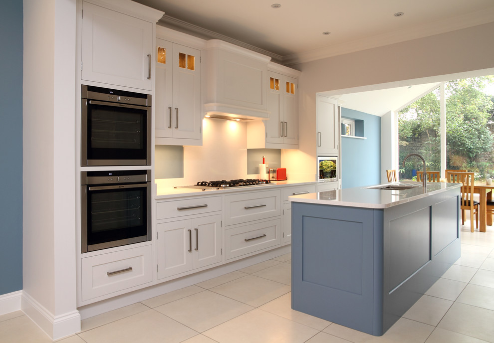 Design ideas for a mid-sized traditional galley eat-in kitchen in Hertfordshire with an undermount sink, shaker cabinets, white cabinets, white splashback and with island.