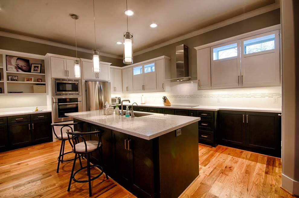Transitional l-shaped medium tone wood floor open concept kitchen photo in Houston with a double-bowl sink, shaker cabinets, black cabinets, marble countertops, white backsplash, marble backsplash, stainless steel appliances, an island and white countertops