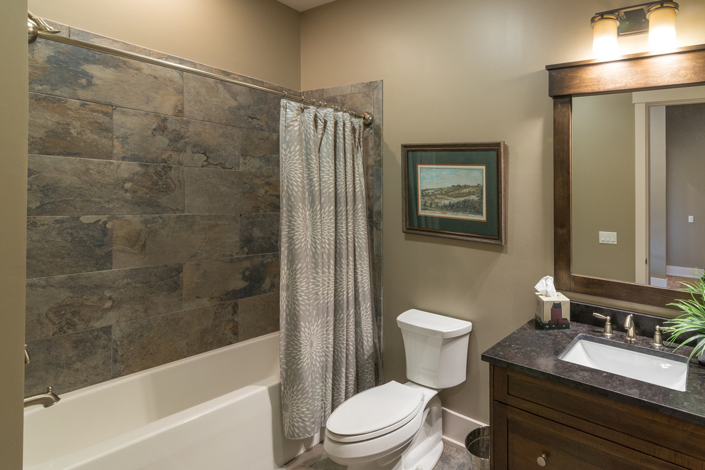 Small transitional bathroom in Other with shaker cabinets, dark wood cabinets, an alcove tub, a shower/bathtub combo, a two-piece toilet, stone tile, beige walls, an undermount sink, multi-coloured floor and a shower curtain.