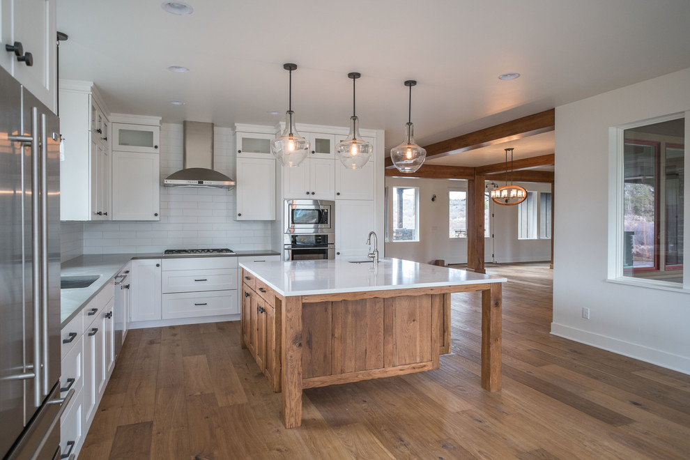 Mid-sized transitional l-shaped medium tone wood floor eat-in kitchen photo with an undermount sink, shaker cabinets, medium tone wood cabinets, quartz countertops, white backsplash, subway tile backsplash, stainless steel appliances and an island