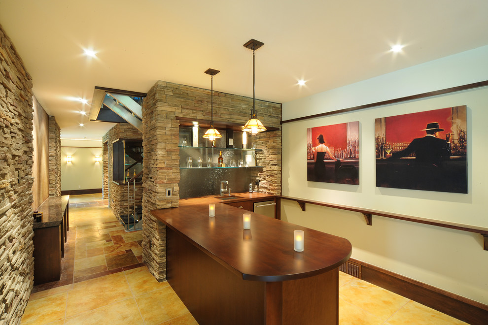 Inspiration for a large arts and crafts galley seated home bar in Burlington with an undermount sink, flat-panel cabinets, dark wood cabinets, wood benchtops, glass sheet splashback, travertine floors and brown benchtop.