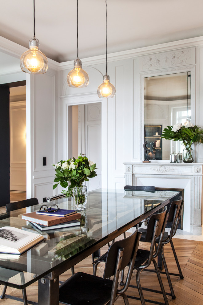 This is an example of a large contemporary open plan dining in Paris with light hardwood floors, a standard fireplace, white walls, a stone fireplace surround and beige floor.