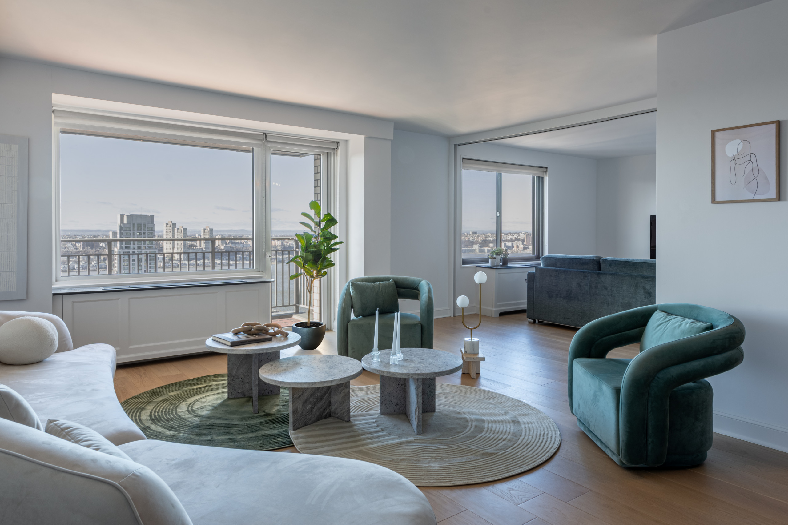 This living space is a perfect blend of modern sophistication and inviting comfort. A curvaceous cream sofa anchors the room, complemented by bold green velvet armchairs for a touch of color. Layered