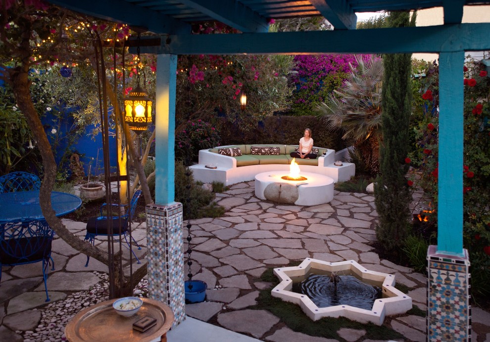 Design ideas for a mid-sized eclectic backyard patio in Los Angeles with a fire feature, natural stone pavers and a pergola.