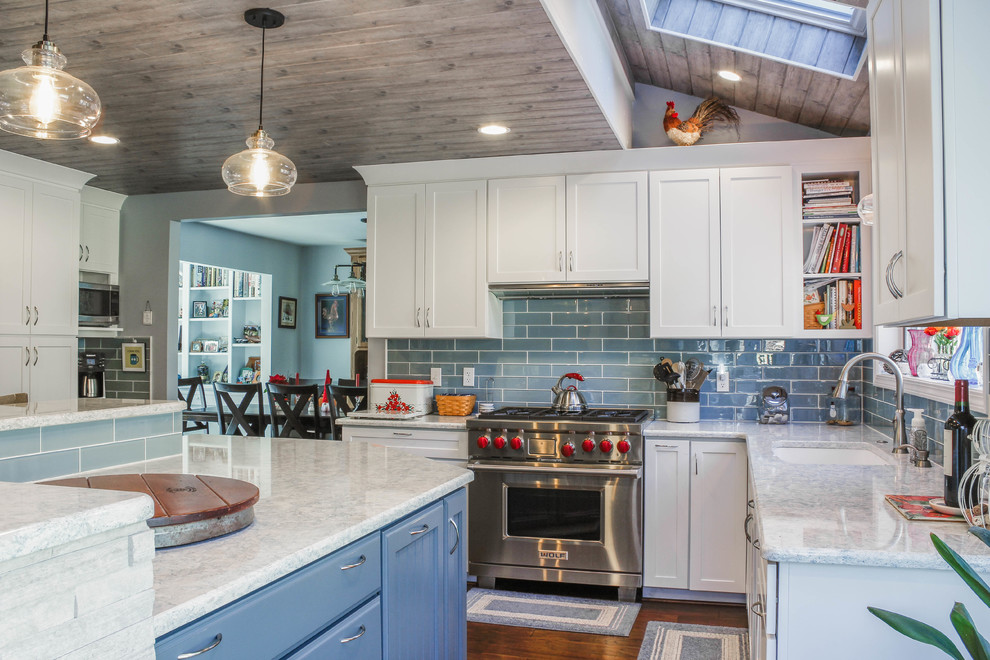 This is an example of a large traditional u-shaped eat-in kitchen in Detroit with an undermount sink, shaker cabinets, blue cabinets, quartz benchtops, blue splashback, glass tile splashback, stainless steel appliances, medium hardwood floors, with island, brown floor and grey benchtop.