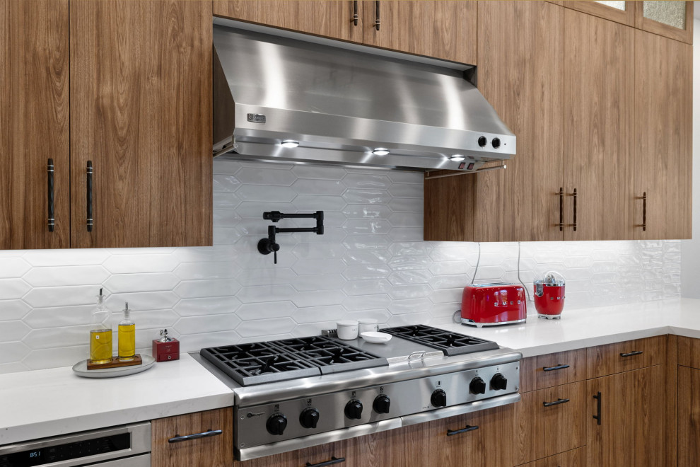 Example of a mountain style l-shaped slate floor and beige floor enclosed kitchen design with a single-bowl sink, flat-panel cabinets, medium tone wood cabinets, quartzite countertops, white backsplash, glass sheet backsplash, stainless steel appliances, a peninsula and white countertops
