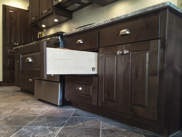 Example of a mid-sized mountain style galley slate floor and beige floor eat-in kitchen design with raised-panel cabinets, dark wood cabinets, granite countertops, an undermount sink, stainless steel appliances and no island