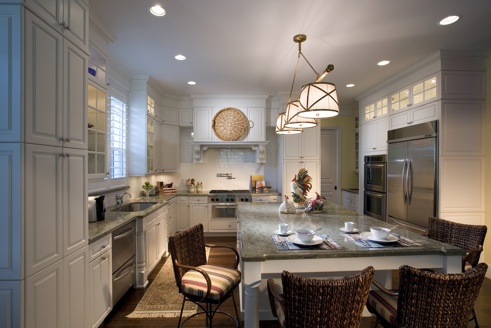Design ideas for a traditional u-shaped kitchen in Miami with stainless steel appliances, subway tile splashback, an undermount sink, raised-panel cabinets, white cabinets and white splashback.