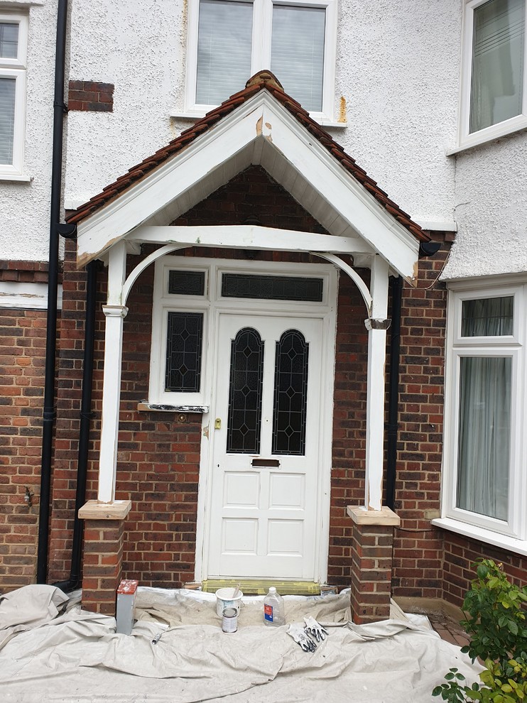Inspiration for a mid-sized traditional front door in London with red walls, concrete floors, a single front door, a white front door, grey floor, recessed and brick walls.