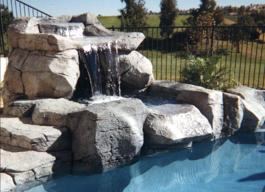 Design ideas for a mid-sized country backyard custom-shaped natural pool in Los Angeles with a hot tub and natural stone pavers.