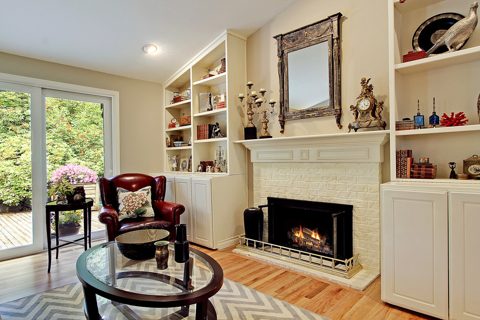 This is an example of a traditional living room in Seattle with beige walls, a standard fireplace and a brick fireplace surround.