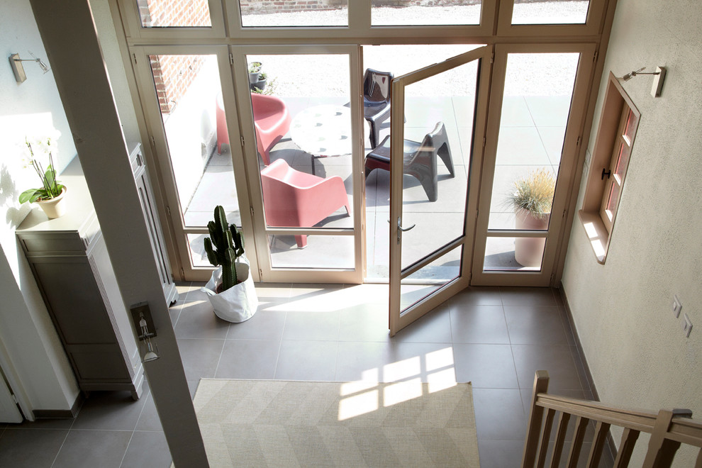 This is an example of a small country foyer in Lille with white walls, ceramic floors, a double front door and grey floor.