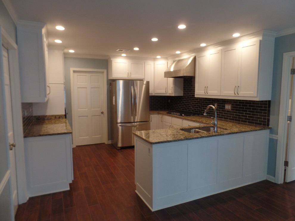 Large transitional u-shaped porcelain tile eat-in kitchen photo with an undermount sink, shaker cabinets, white cabinets, quartz countertops, green backsplash, glass tile backsplash, stainless steel appliances and a peninsula