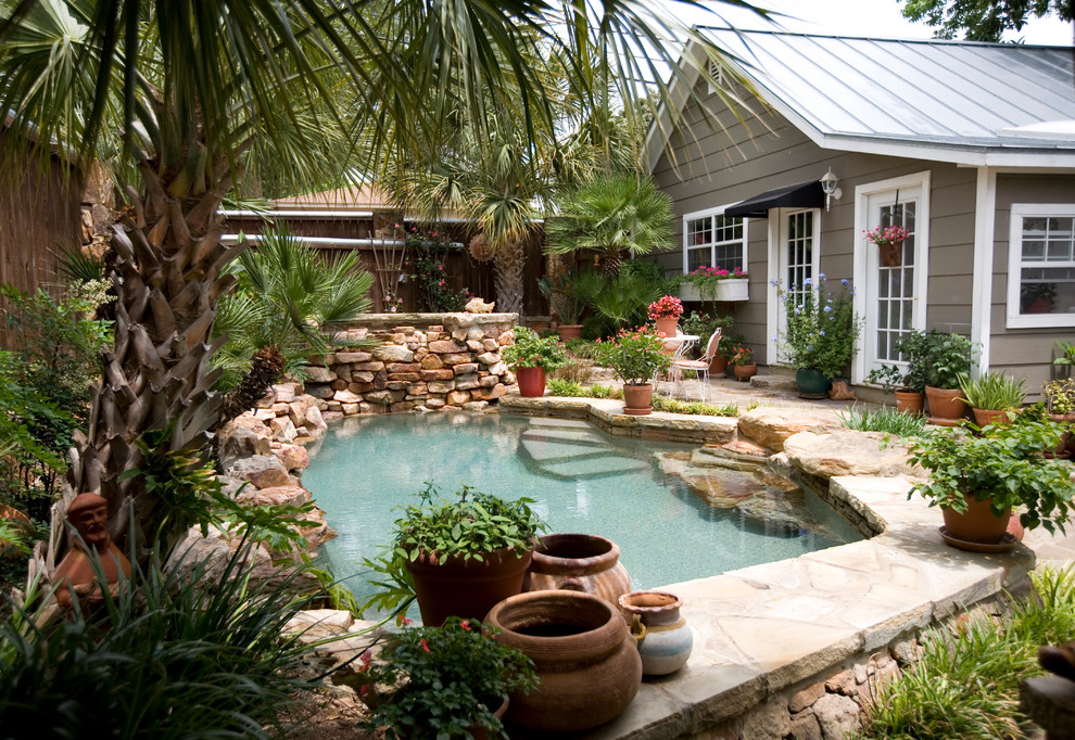This is an example of a small country backyard custom-shaped natural pool in Austin with natural stone pavers.