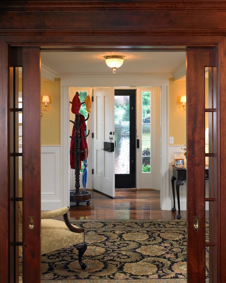 Photo of a mid-sized beach style foyer in Boston with yellow walls, medium hardwood floors, a pivot front door and a white front door.