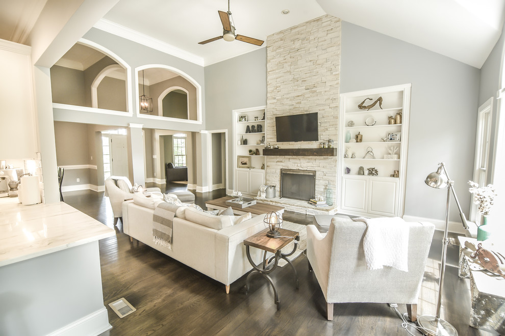 Design ideas for a large transitional open concept living room in Charlotte with grey walls, dark hardwood floors, a standard fireplace, a stone fireplace surround and a wall-mounted tv.
