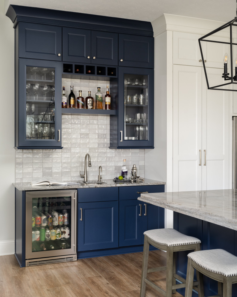 Design ideas for a mid-sized modern galley bar cart in Indianapolis with an undermount sink, glass-front cabinets, blue cabinets, white splashback, ceramic splashback and medium hardwood floors.