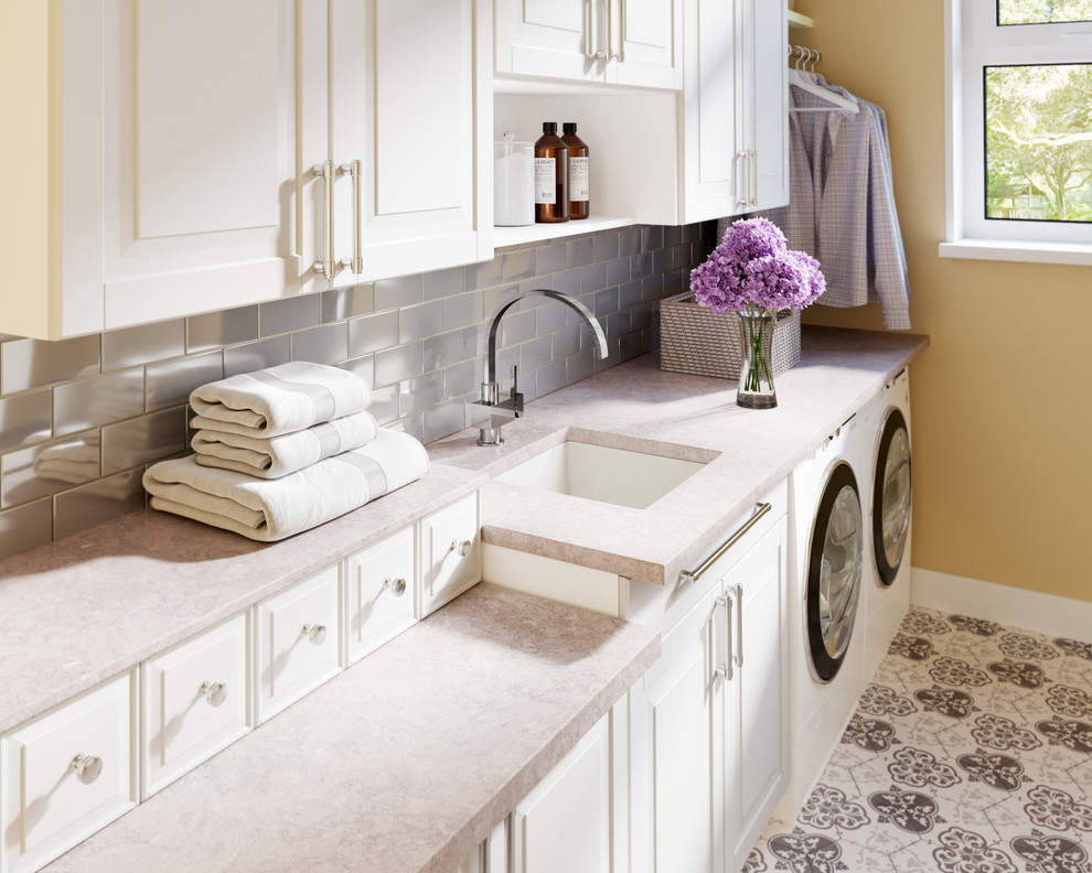 This is an example of a laundry room in Other with raised-panel cabinets, an undermount sink and beige walls.
